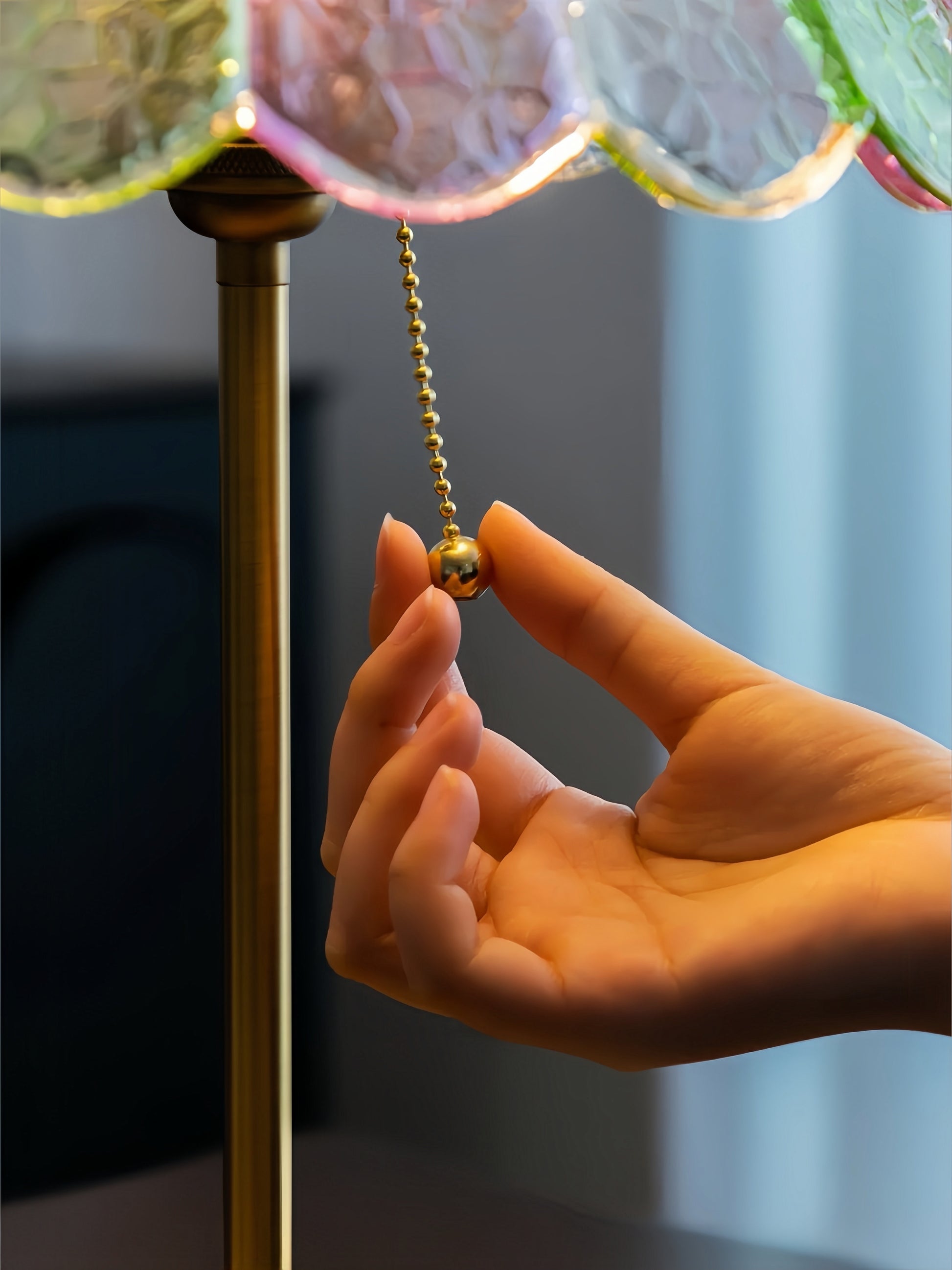 Hand adjusting a light fixture with colorful glass shades.