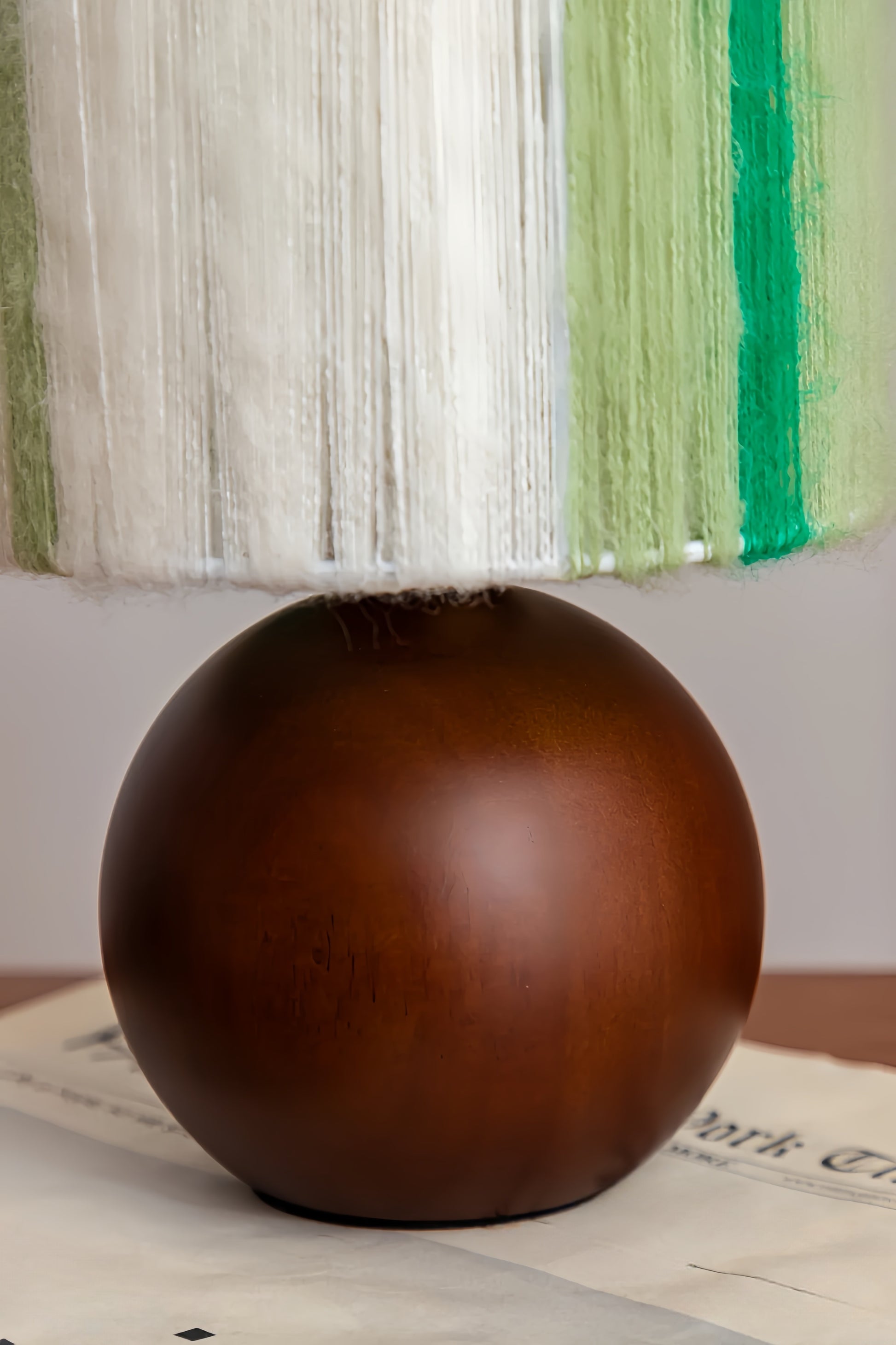 Brown spherical lamp base on a newspaper with a striped fabric background