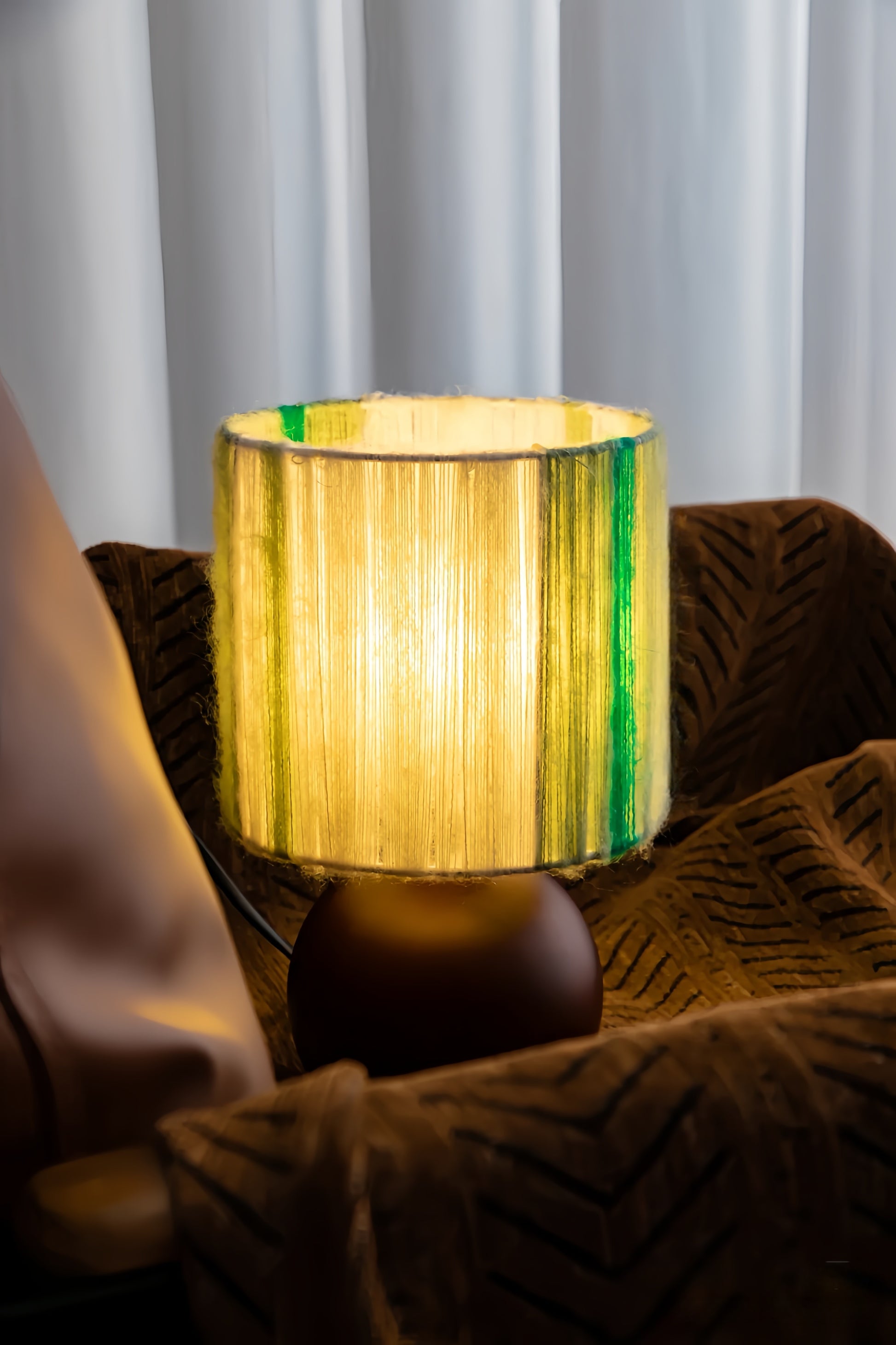 Mohair lamp with a green and yellow striped shade on a couch