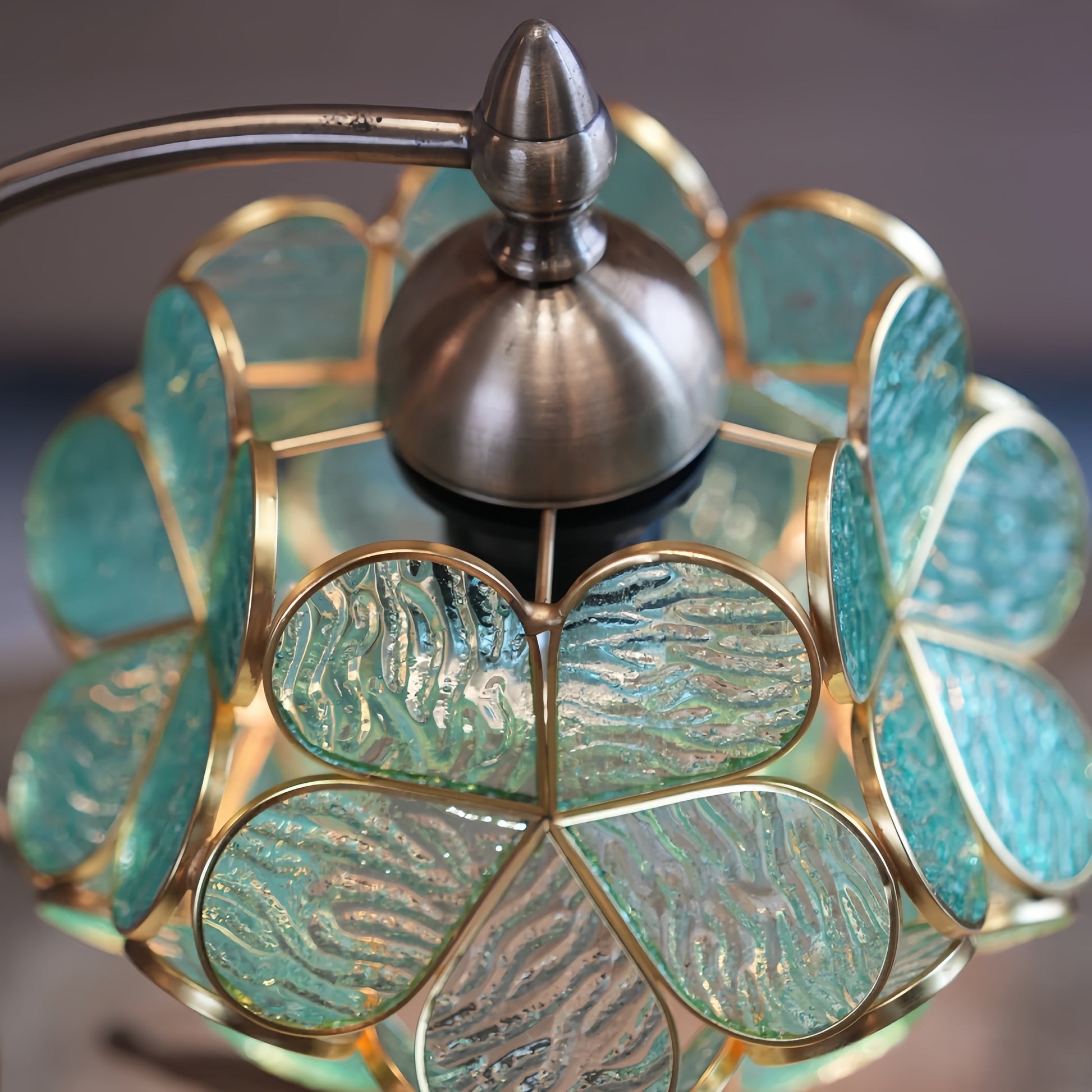 Decorative teal and gold MCM lamp with a blurred background