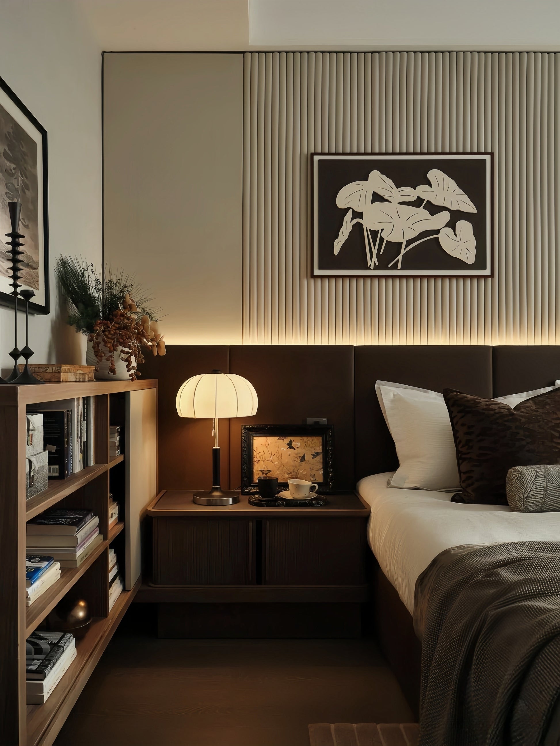 Warm mid-century modern bedroom with pleated table lamp on wooden nightstand, bookshelves, and layered neutral bedding