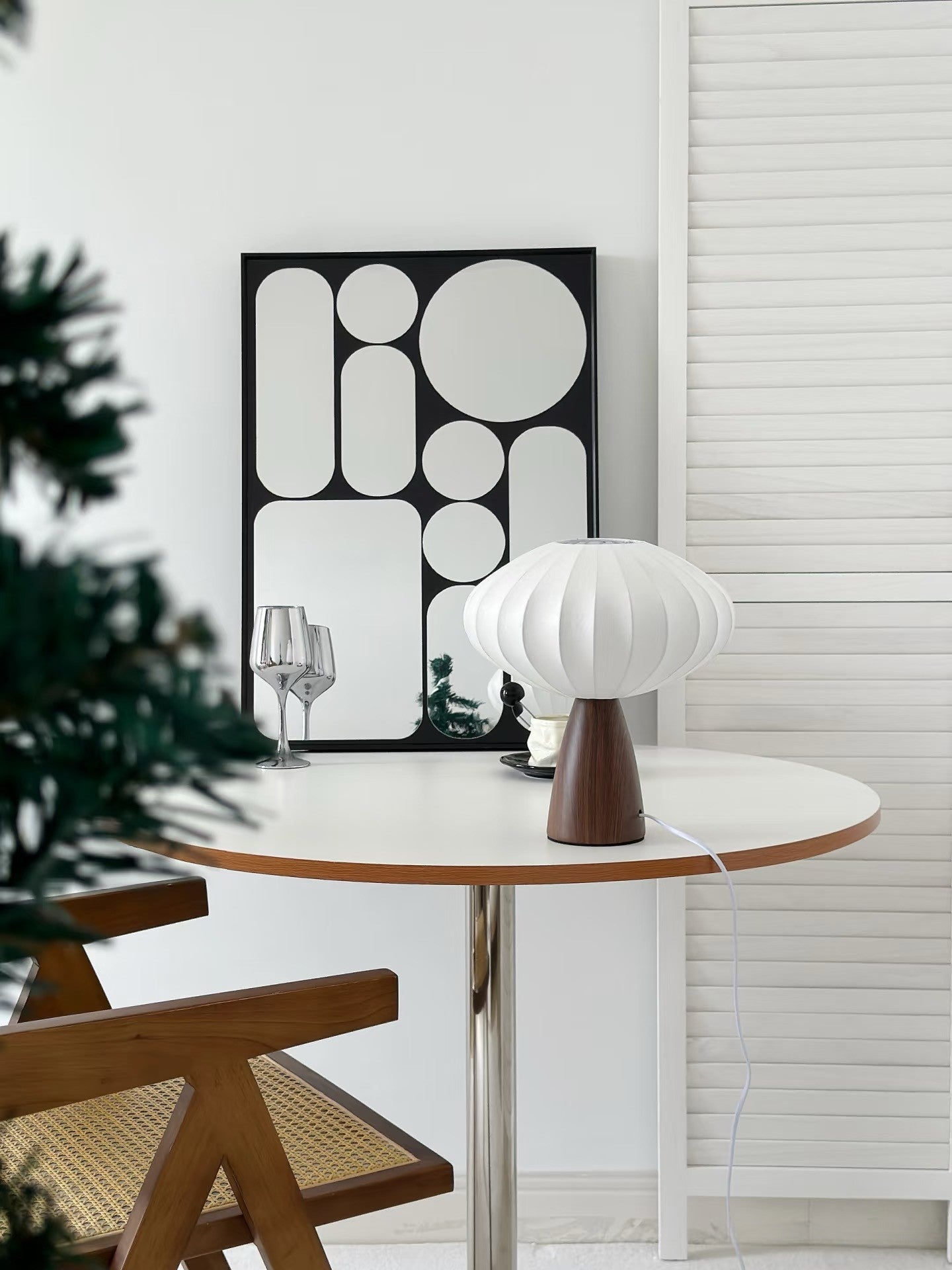 Round dining table with a Japandi lamp and chairs in a room with abstract wall art.